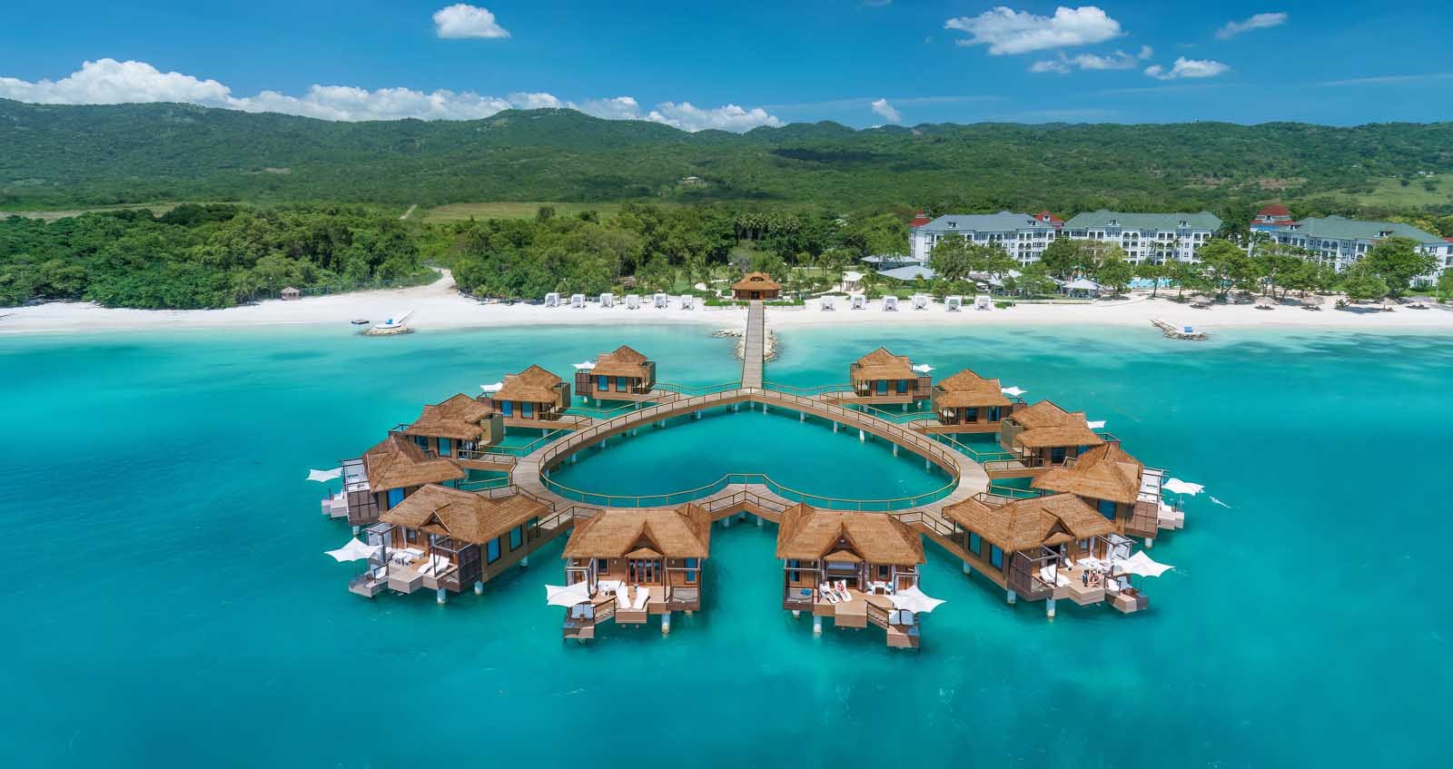 Heart-shaped overwater bungalow cluster at Sandals South Coast, Jamaica with glass floor panels and floating hammock
