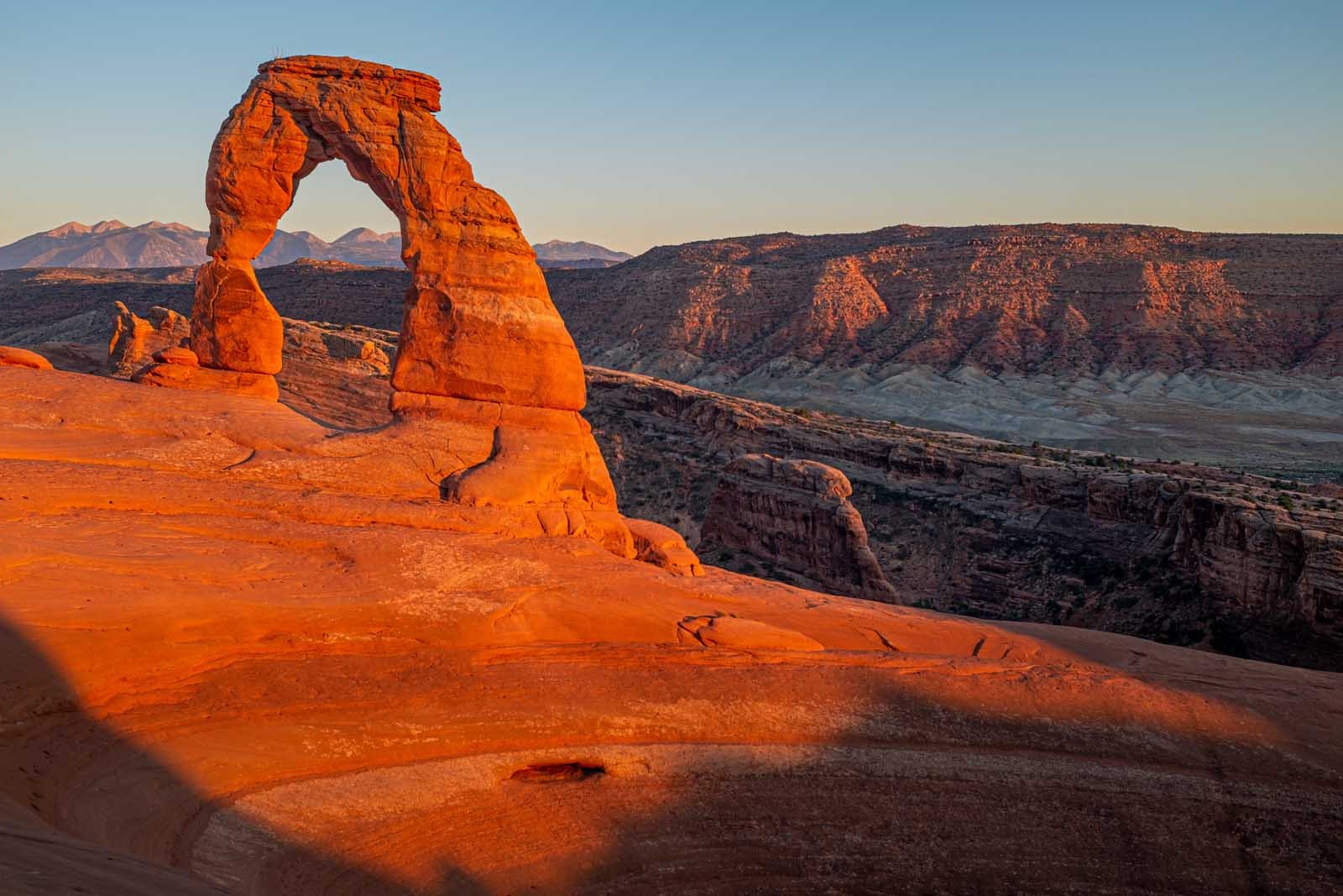 Delicate Arch hike in Arches National Park at sunrise with dramatic desert backdrop