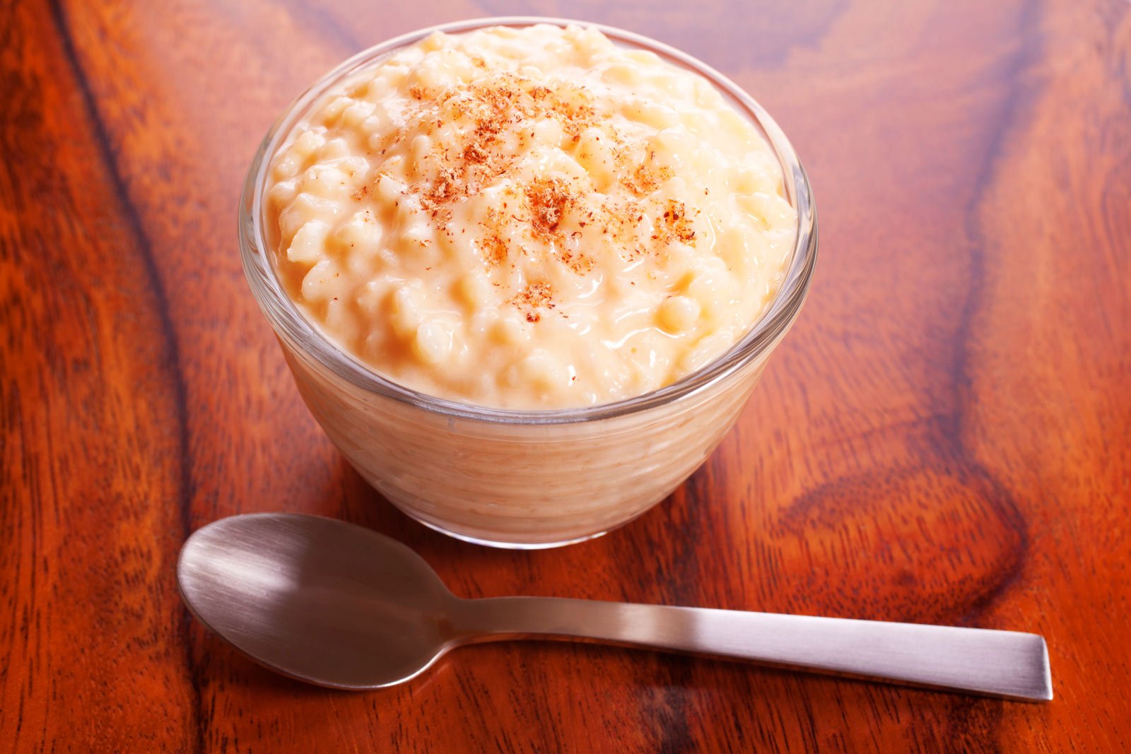 A white bowl of creamy Arroz con Leche (Cuban rice pudding), garnished with a sprinkle of ground cinnamon