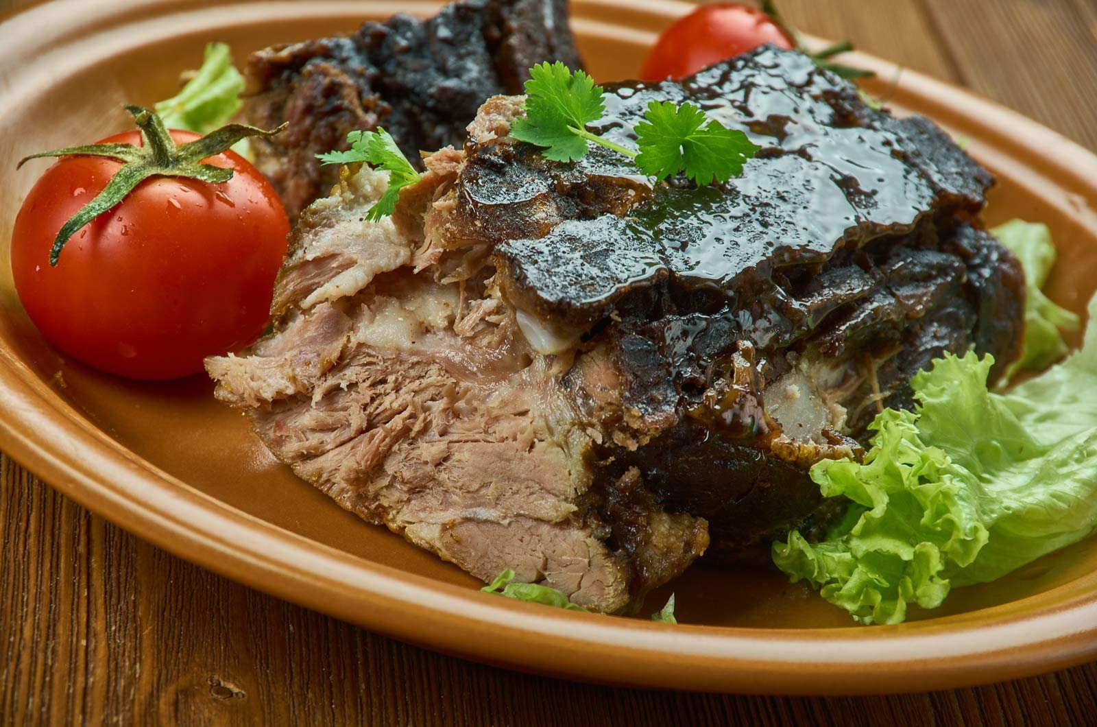 A platter of Lechon Asado, showcasing crispy-skinned roast pork pieces with a side of mojo sauce and lime wedges.