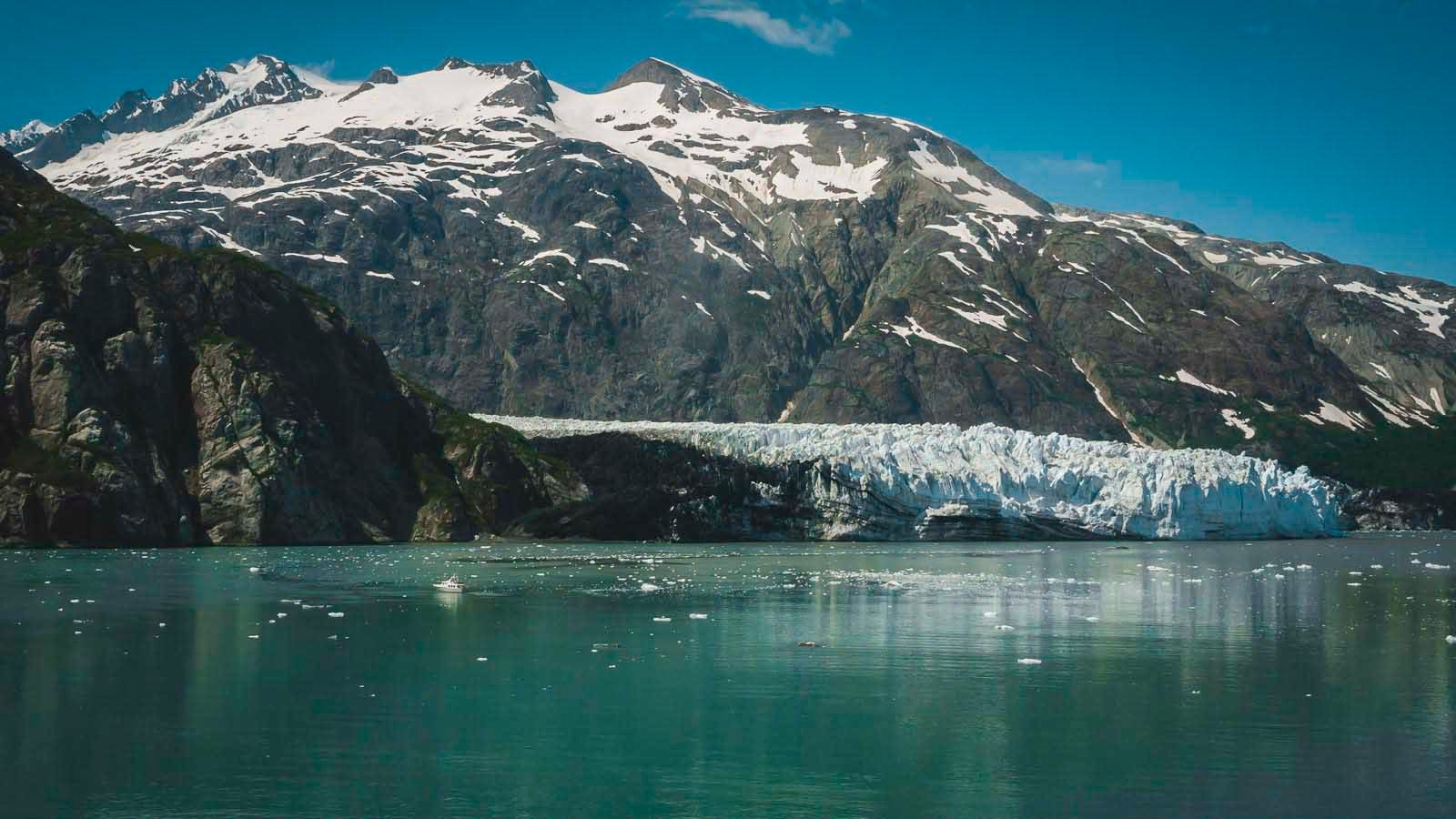 A large tidewater glacier calving a chunk of ice into the calm waters of Glacier Bay National Park, Alaska.