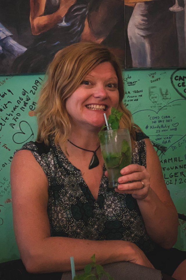 Enjoying A tall glass of a refreshing Cuban Mojito, filled with ice, fresh mint leaves, lime wedges, and a straw in the streets of Havana
