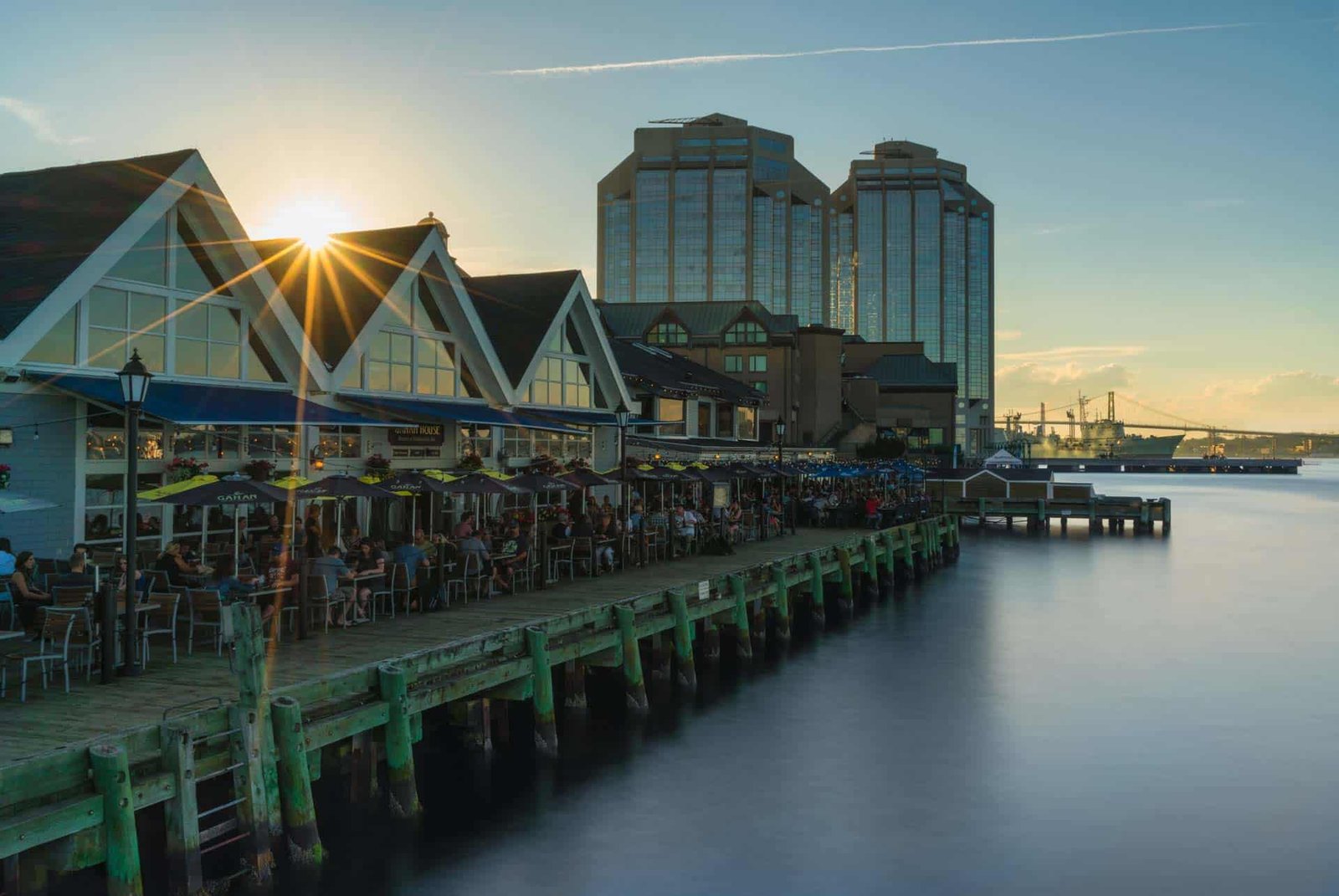People strolling along the vibrant Halifax waterfront boardwalk on a sunny day.
