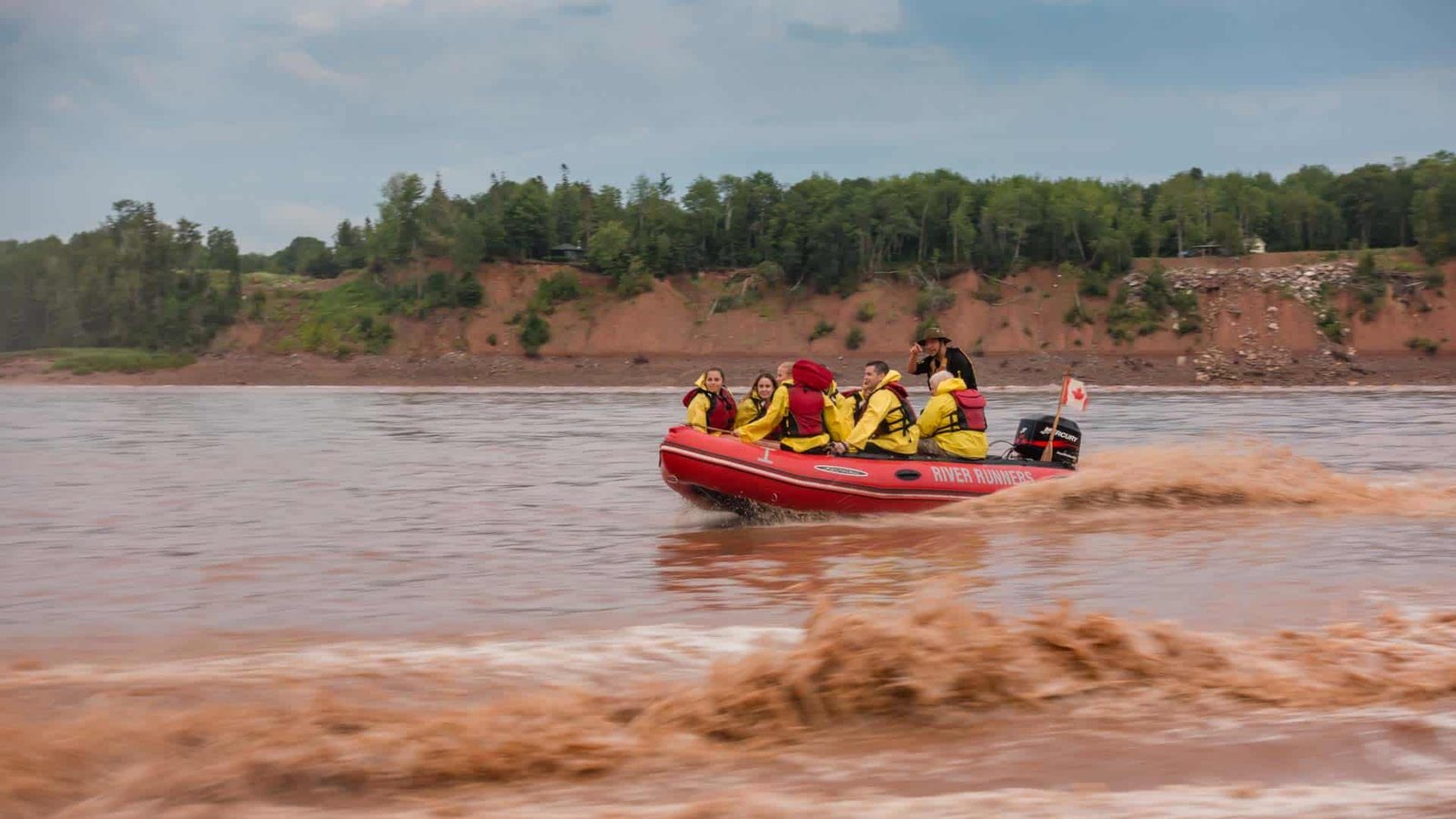 A zodiac full of people tidal bore rafting on a large wave on the Shubenacadie River.