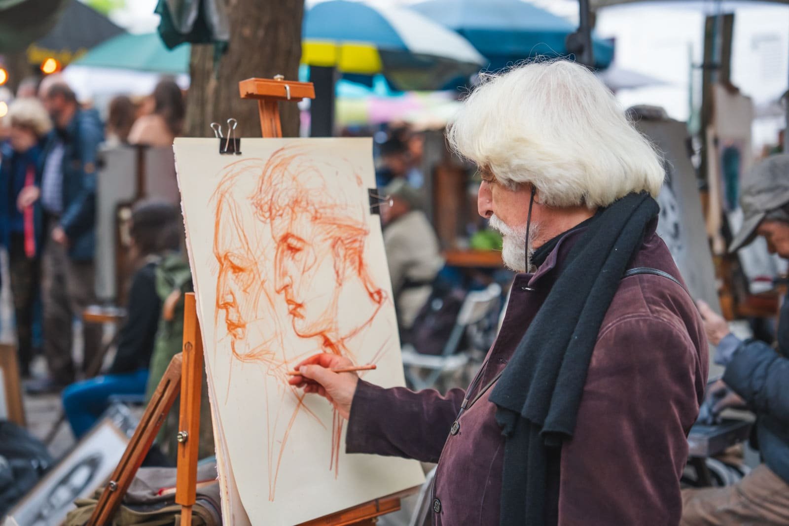 Dave and Deb watching an artist paint at an easel in the bustling Place du Tertre in Montmartre, Paris.
