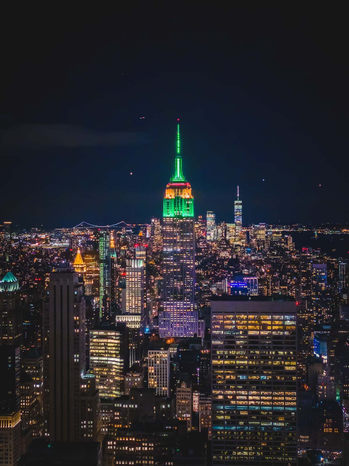 The top of the Empire State Building lit up with festive red and green lights for the Christmas season.
