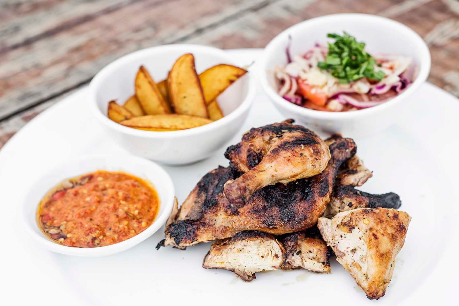 A platter of smoky, charcoal-grilled Piri-Piri chicken, a famous dish from the Algarve region of Portugal.