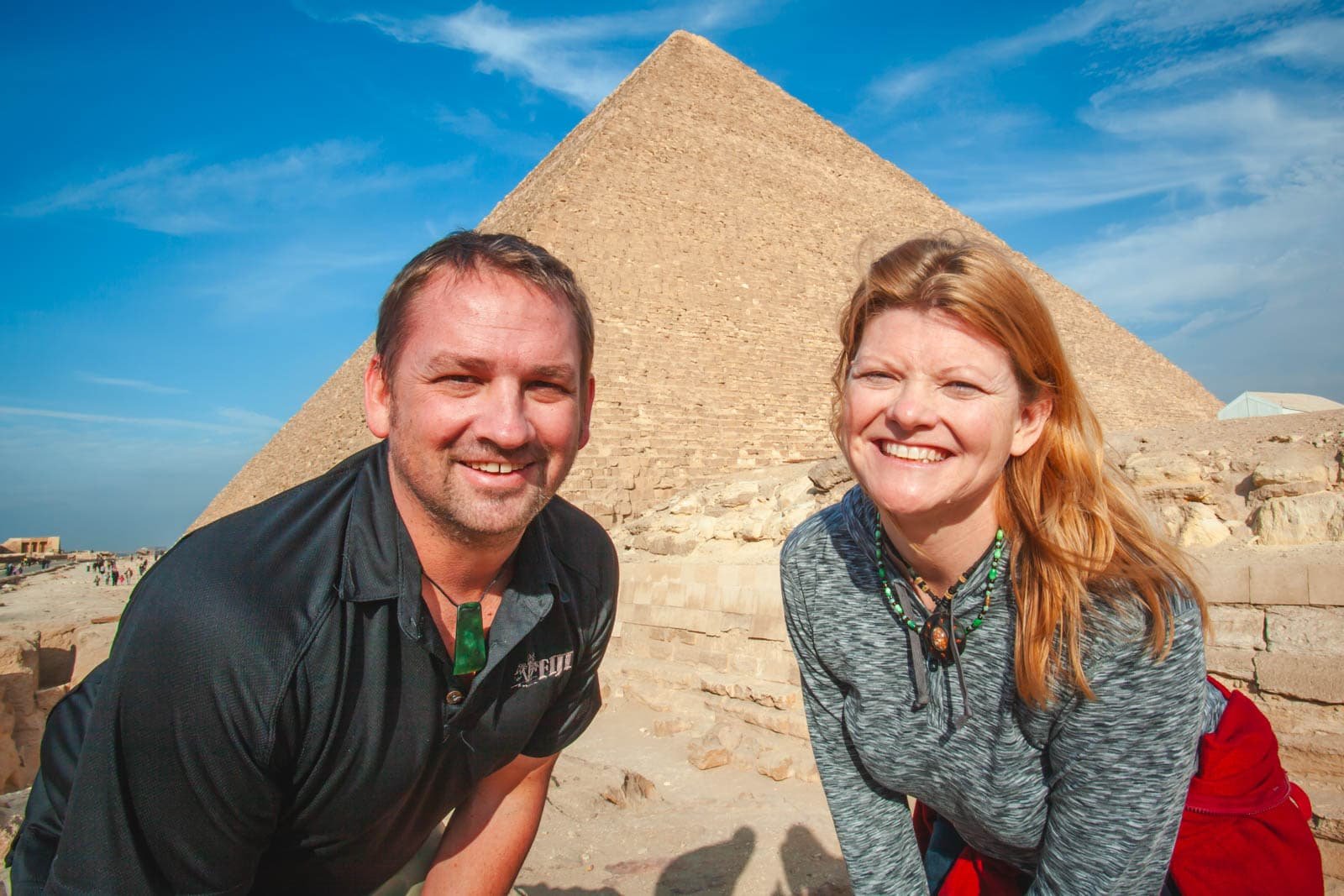 Dave and Deb from The Planet D smiling in front of the Great Pyramids of Giza, illustrating a safe and positive trip to Egypt.